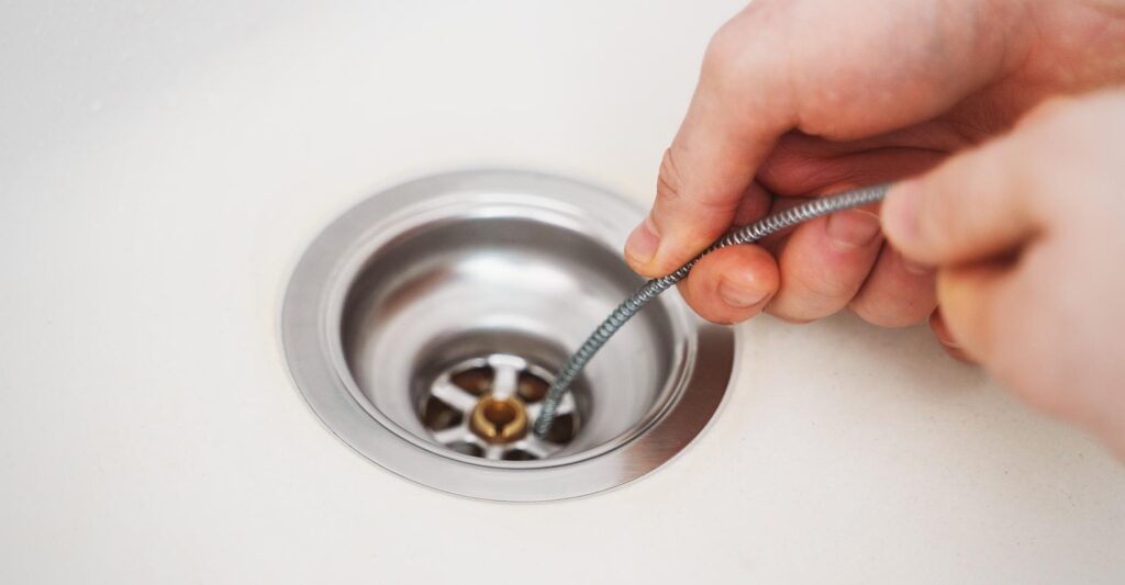 Plumber using a snake to unclog a sink drain