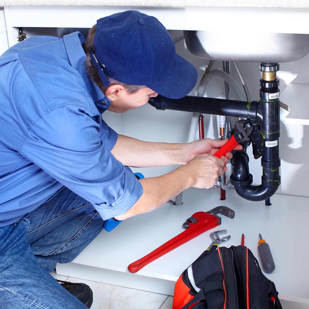 plumber repairing pipes under a sink