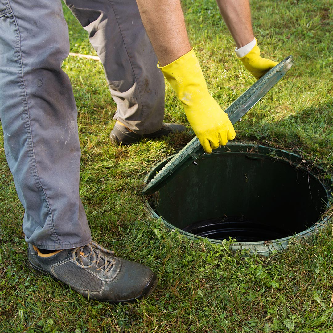 plumber lifting the cover of a septic tank
