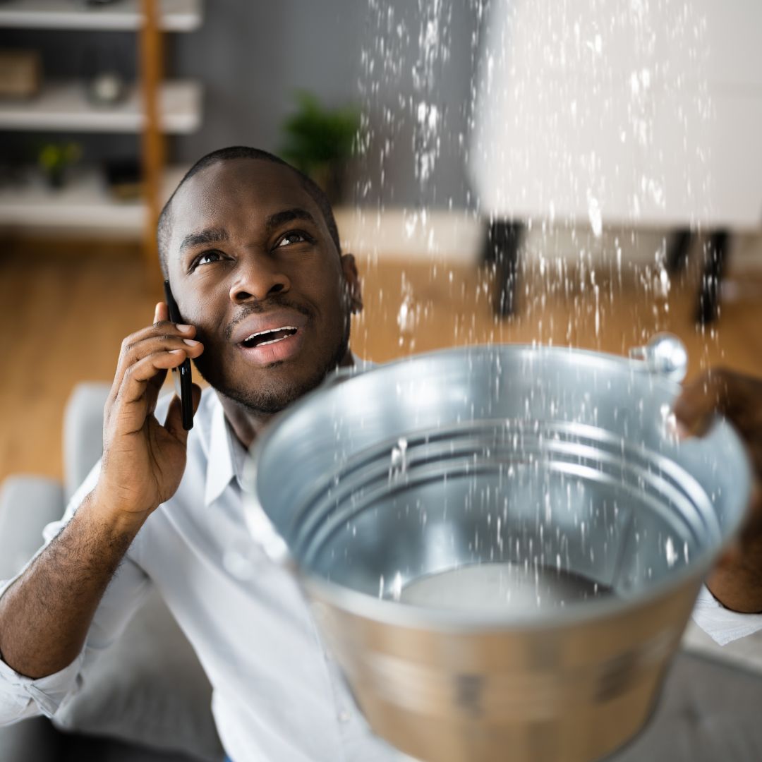 man on the phone while catching water in a bucket
