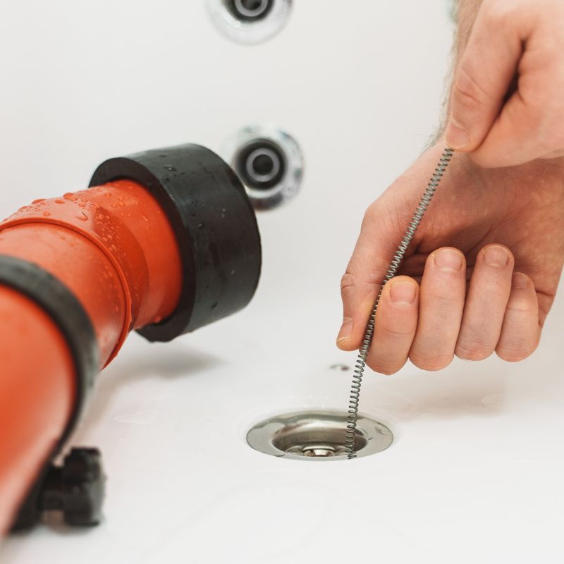 a person snaking a drain