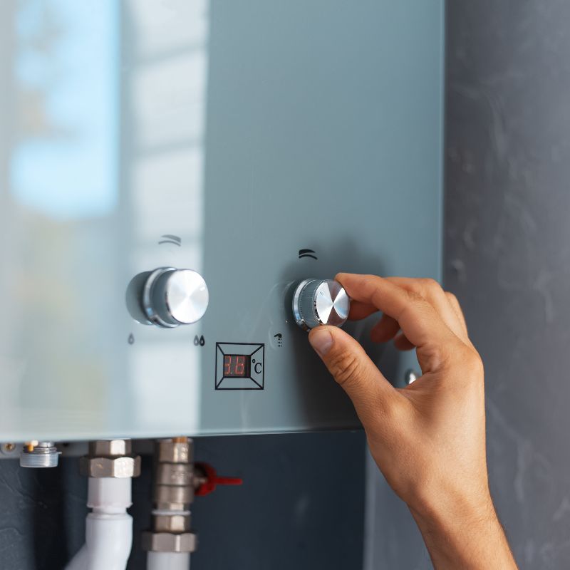 a person adjusting a tankless water heater
