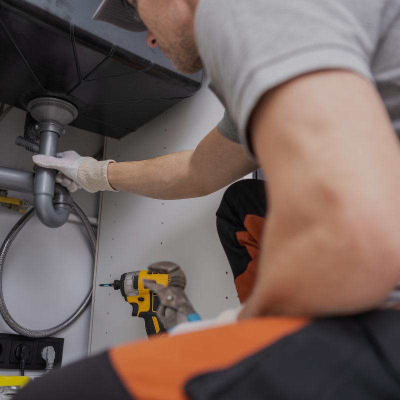 Plumber working under a sink