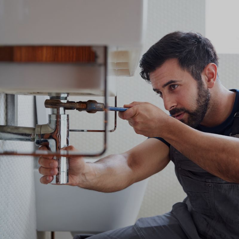A plumber using a wrench on a drain