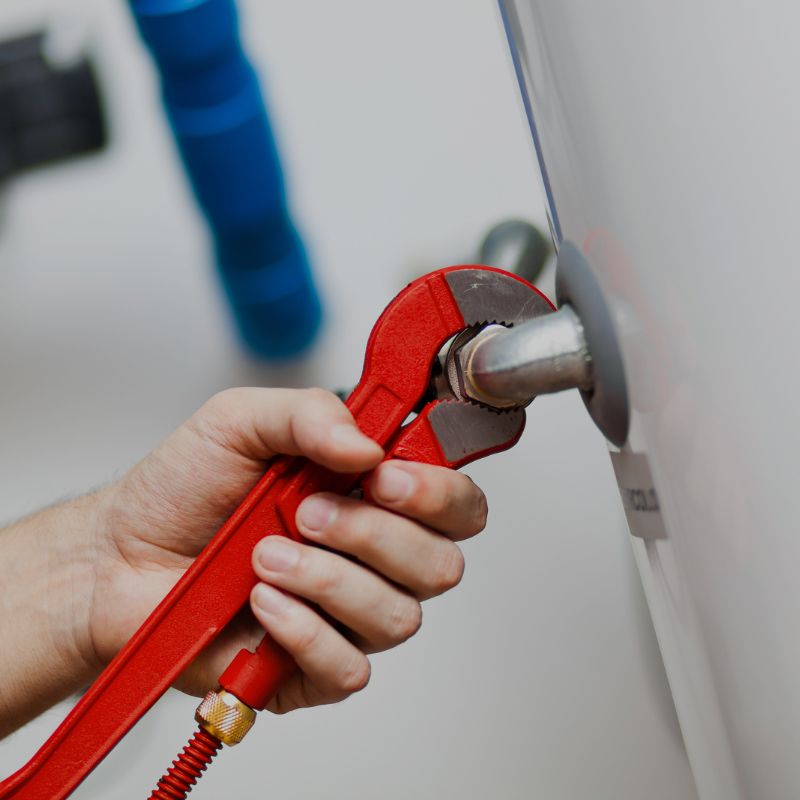 A plumber using a wrench on a water heater