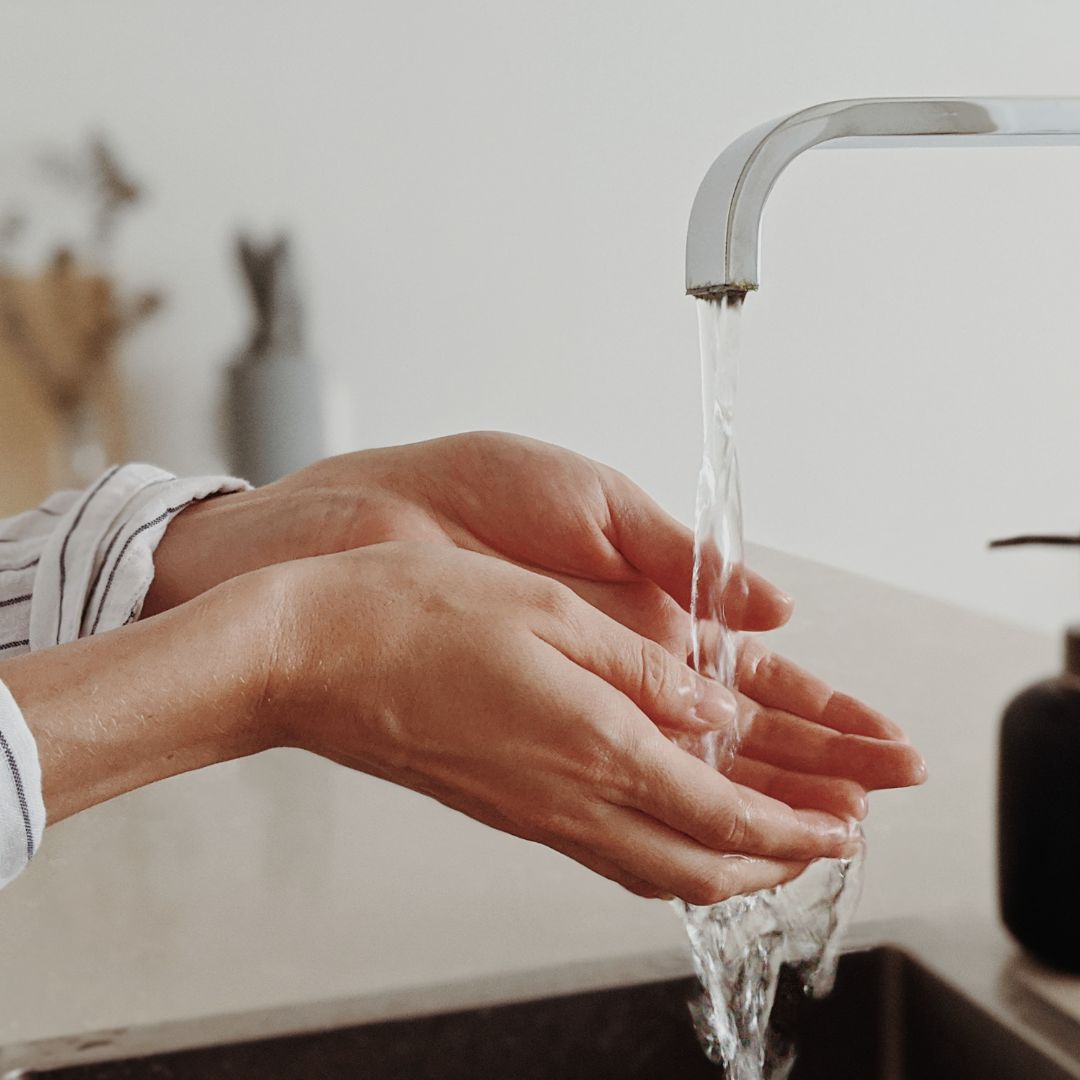 A woman washing her hands in a kitchen sink