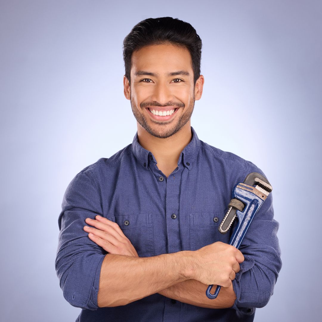 A plumber holding a wrench and smiling at the camera