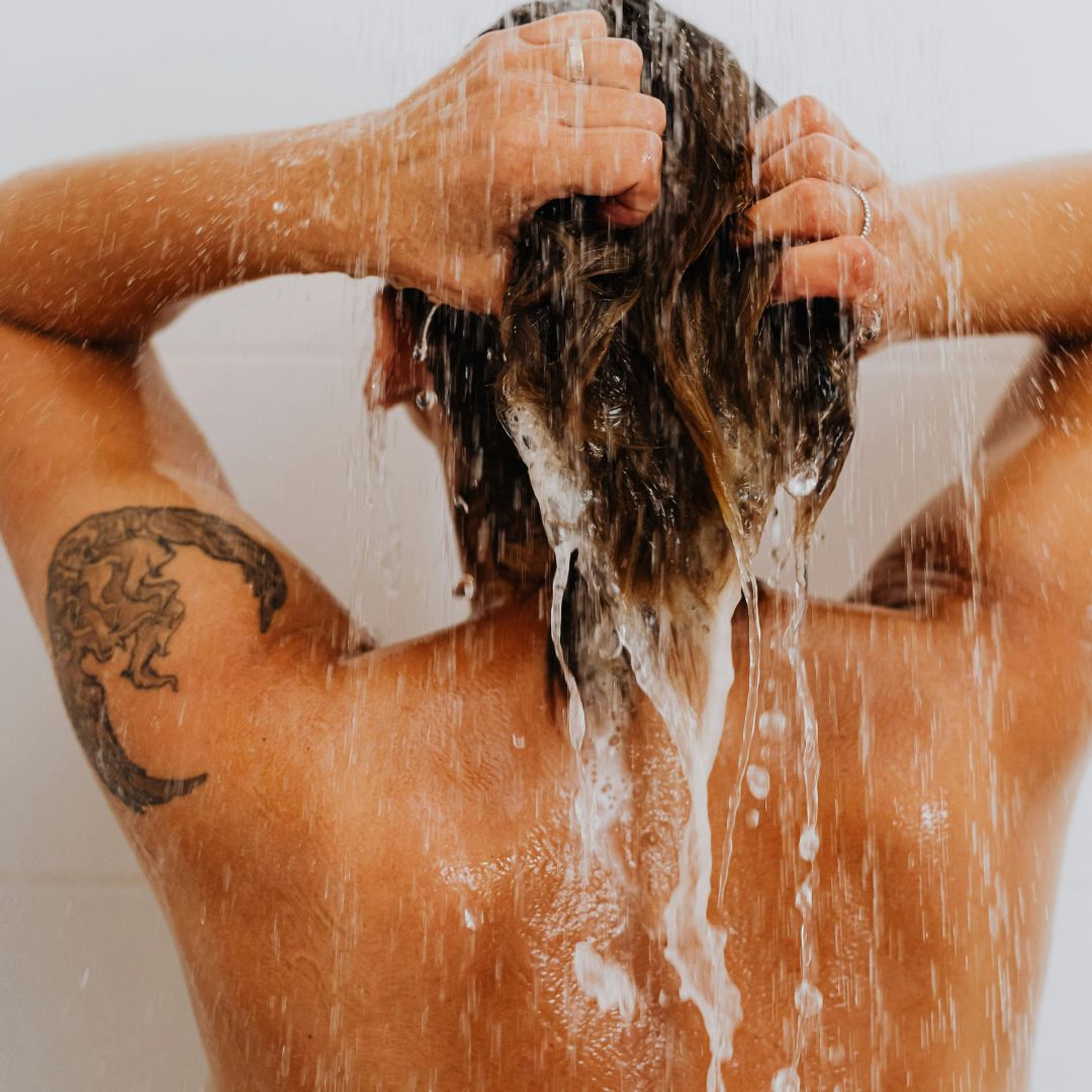 a woman washing her hair in a shower